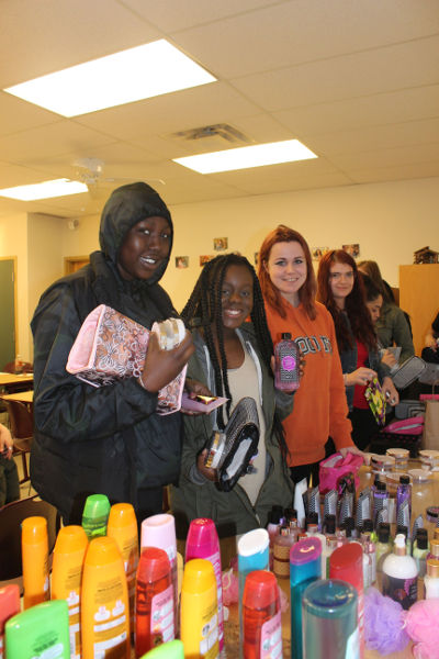 Smiling Youville moms pose with gift bags and bath products that will be used to make their self care toolkits.